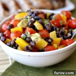 Close-up of a colorful Guacamole Salad in a white bowl, showing fresh vegetables and creamy avocado pieces, ready to be served.