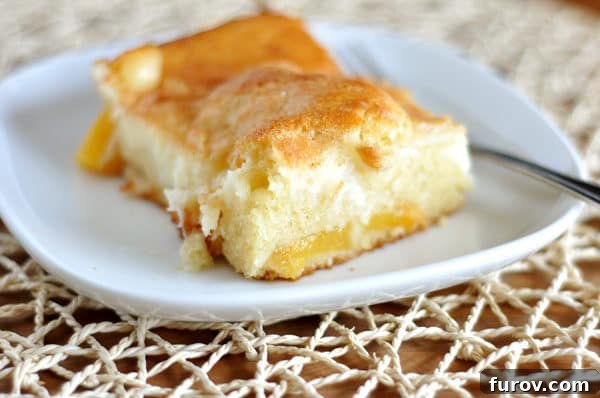 Sun-Kissed Peach Dream Cake 3 A close-up view of a perfect slice of Peaches and Cream Cake on a pristine white plate, showcasing the distinct layers of cake, peaches, and creamy topping, ready to be enjoyed with a fork.