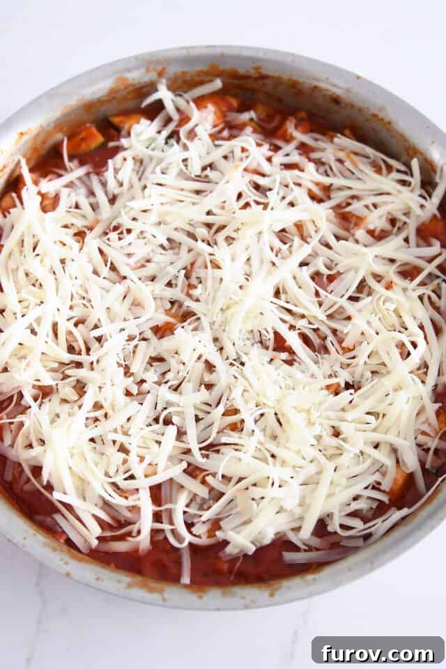 Sizzling Skillet Chicken Zucchini with Italian Cheeses 6 Layer of shredded mozzarella cheese melting over the tomato sauce in a stainless steel skillet.