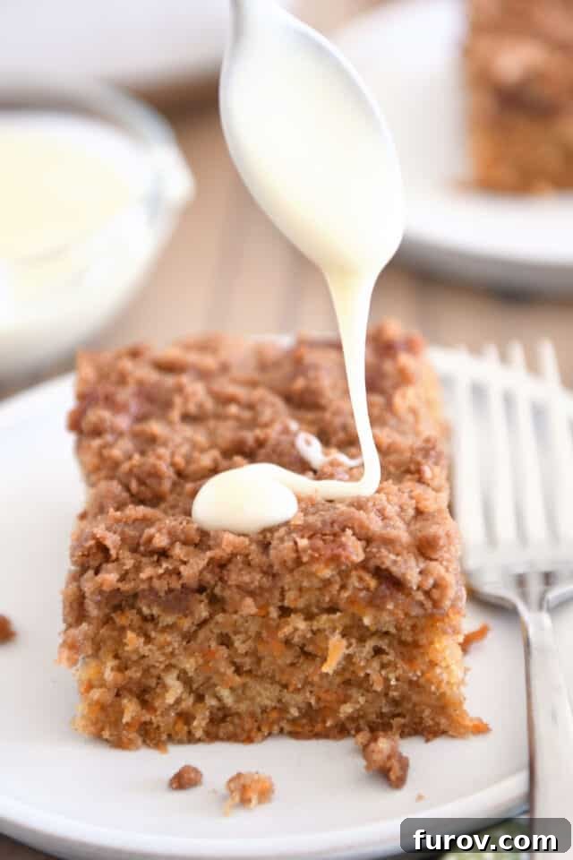Cream cheese glaze being artfully drizzled over a square of carrot cake coffee cake on a white plate, adding the final touch of sweetness and beauty.