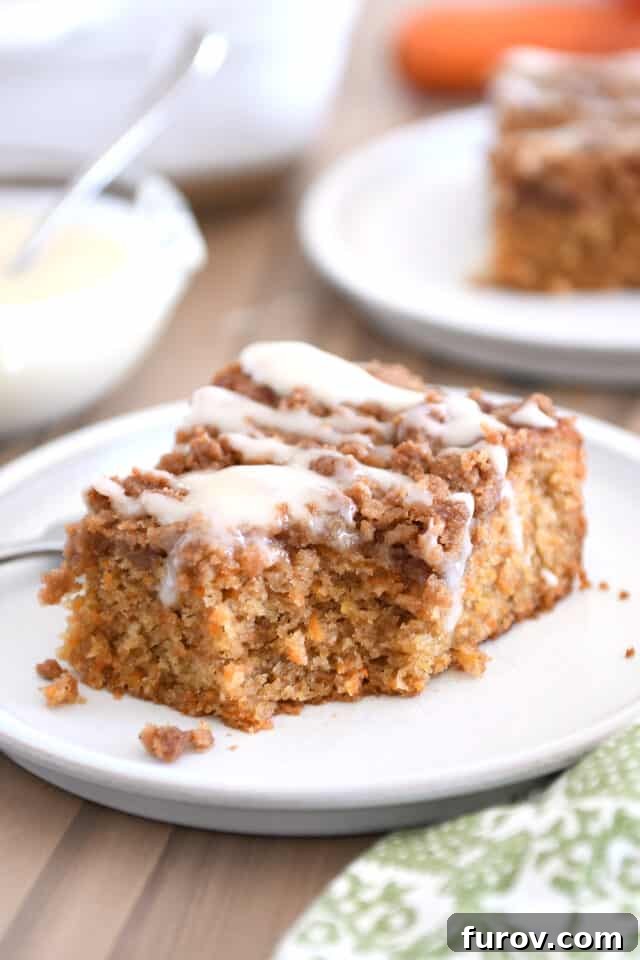A slice of carrot cake coffee cake on a white plate with cream cheese drizzle, a bite already taken, showing its delicious layers and moist texture.