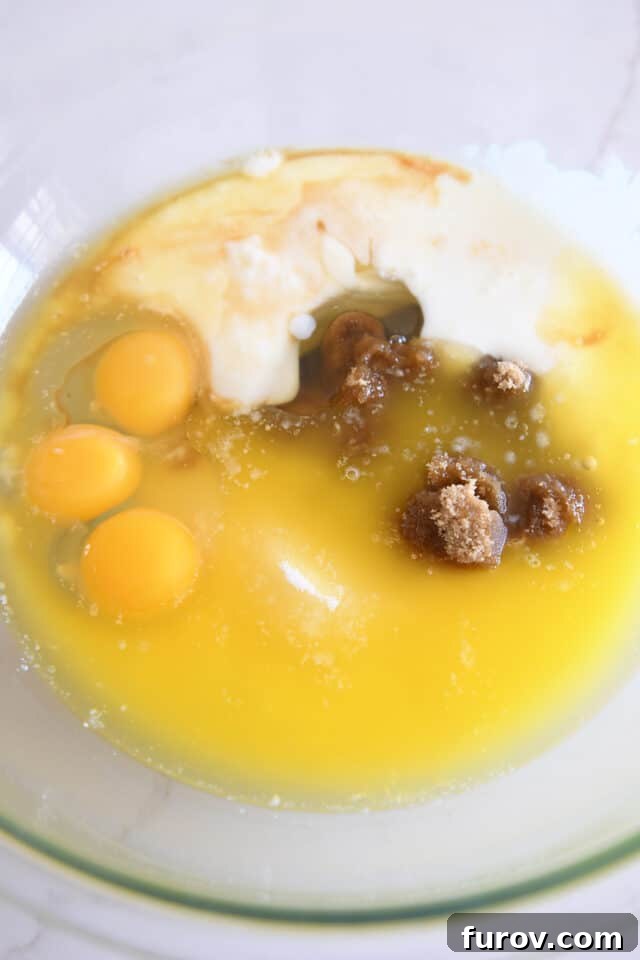 Melted butter, eggs, brown sugar, white sugar, and buttermilk in glass bowl, forming the wet base for the cake.