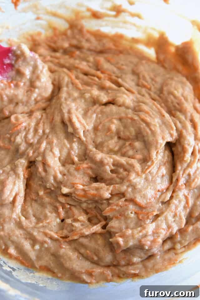 Mixed carrot cake batter in glass bowl, smooth and ready for baking, showcasing its rich texture.