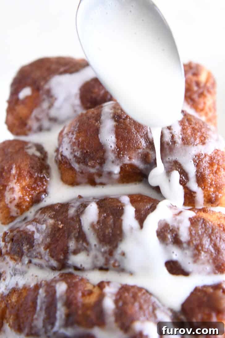 Spoon drizzling glaze over homemade cinnamon pull-apart bread.