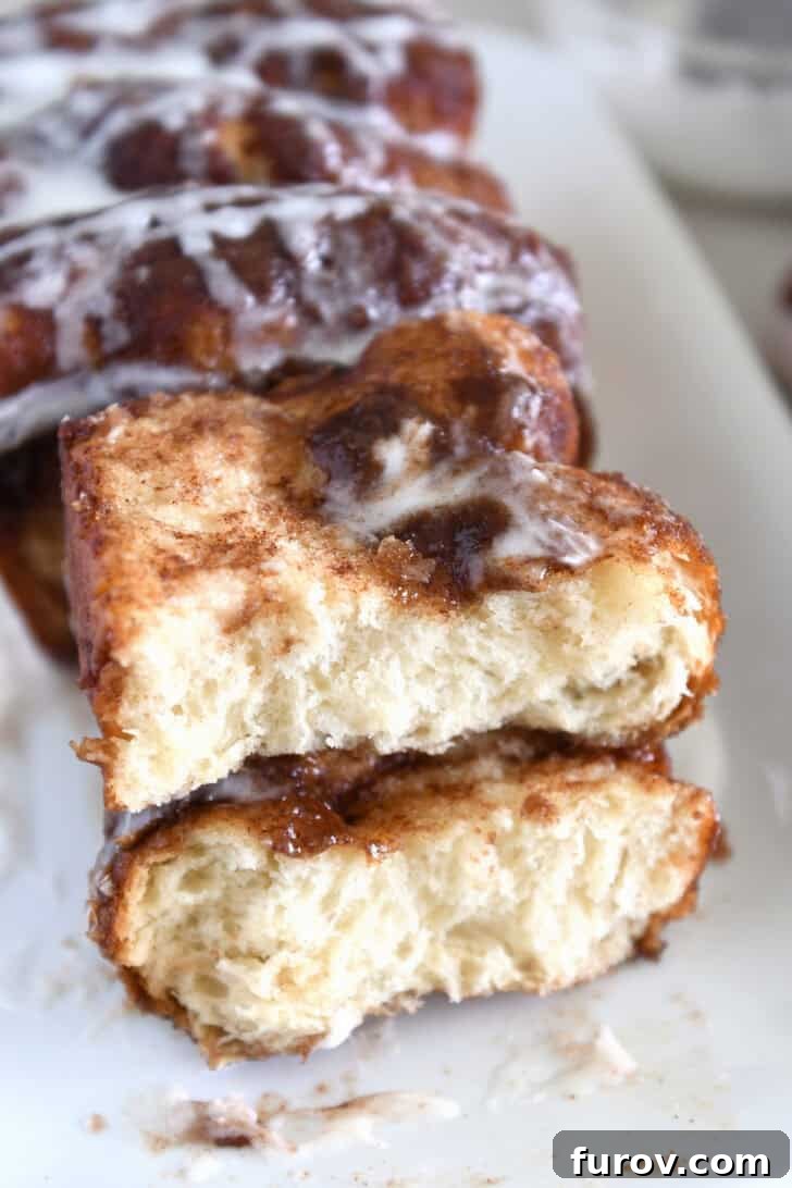 Two half slices of cinnamon bread on white platter with glaze, ready to be enjoyed.