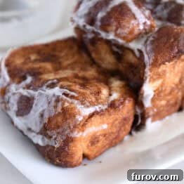 Thick slice of cinnamon bread on white platter with glaze.