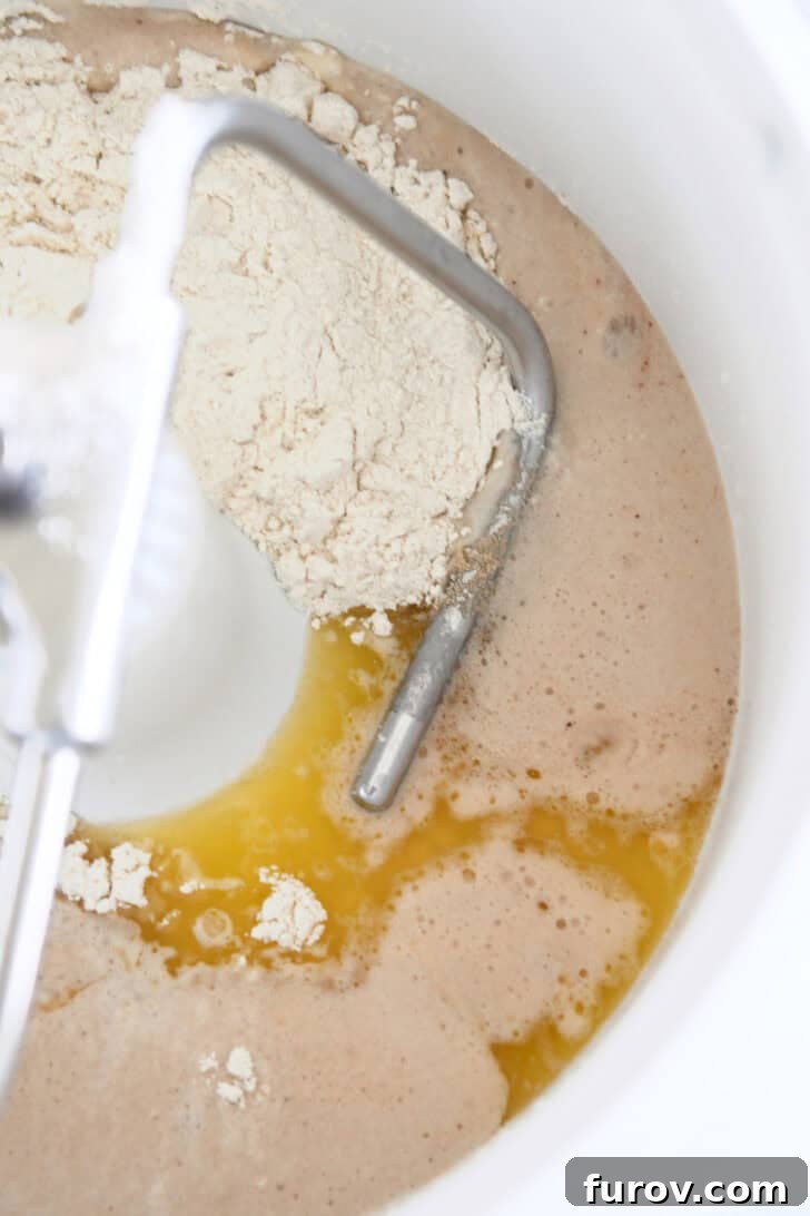 Water, yeast, butter and flour in bosch mixer for cinnamon bread dough.