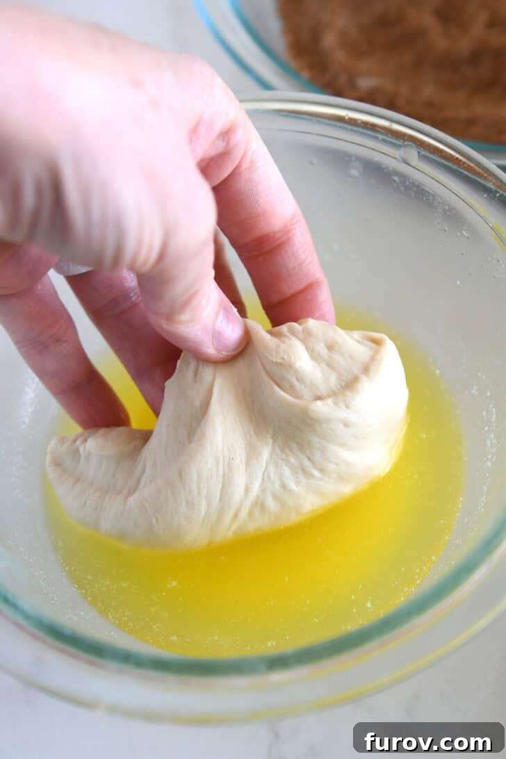 Dipping a piece of bread dough into melted butter for cinnamon bread.