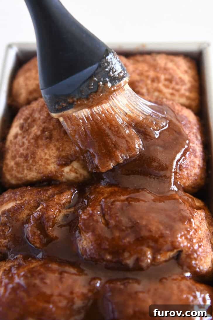 Brushing butter, cinnamon and brown sugar over top of hot baked cinnamon bread.