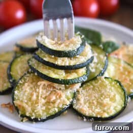 Fork spearing three zucchini rounds on gray plate.