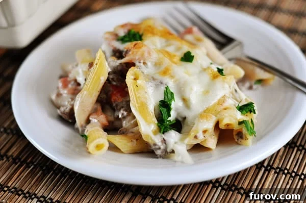 White plate with baked Greek Pastitsio pasta, topped with melted cheese.
