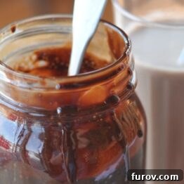 Rich homemade chocolate syrup in a mason jar, perfectly prepared and ready to be enjoyed with milk or other treats.