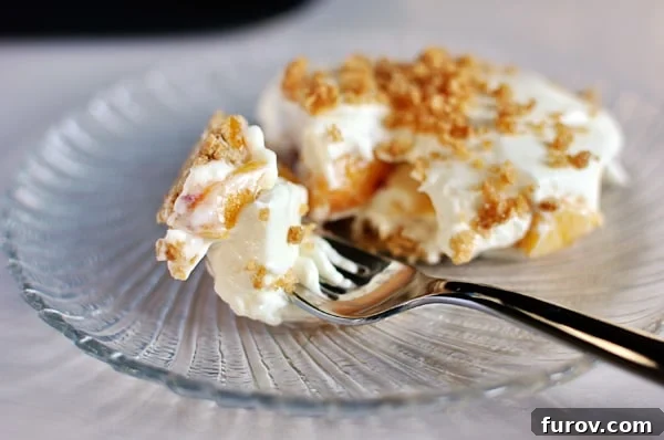 No-Bake Peaches and Cream Bliss 9 A fork taking a delicious bite out of a beautiful peaches and cream dessert, served on an elegant glass plate.