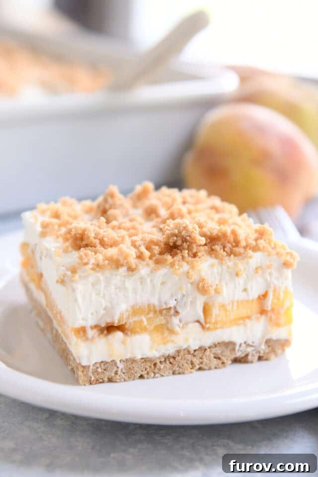 No-Bake Peaches and Cream Bliss 3 A square slice of peaches and cream dessert is presented on a white plate, with a whole peach blurred in the background, emphasizing the fresh fruit.