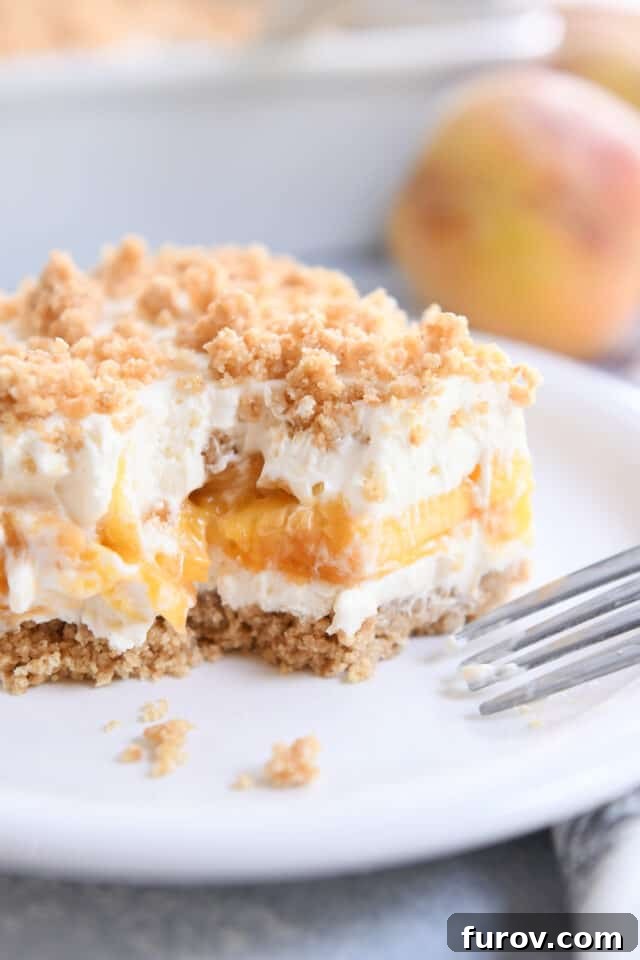 No-Bake Peaches and Cream Bliss 7 A perfectly portioned square of peaches and cream dessert resting on a pristine white plate, with a fork poised for a delicious bite.