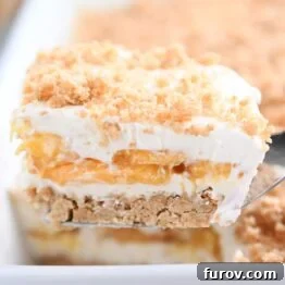 A square slice of no-bake peaches and cream dessert on a metal spatula, ready to be served, highlighting its delicious layers.