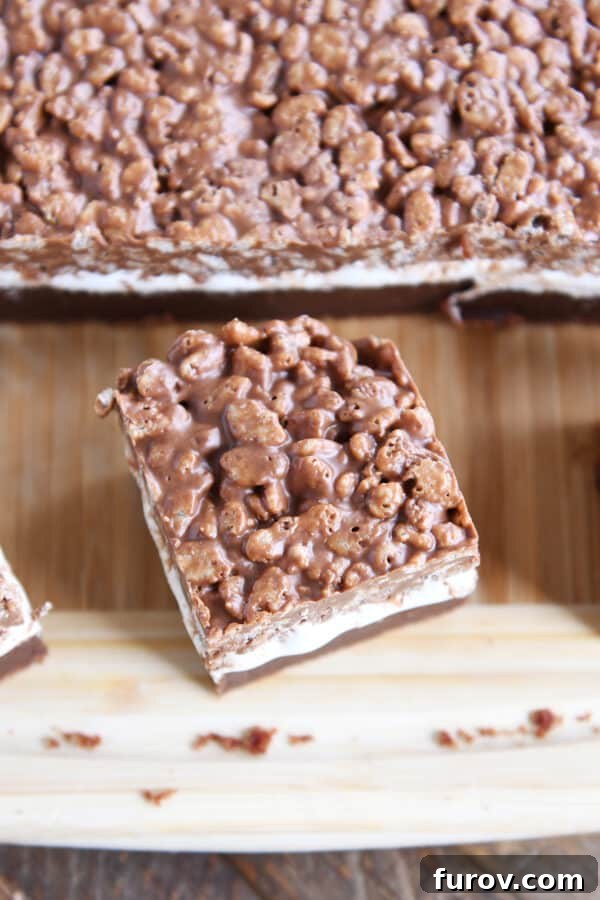A single square of Killer Crunch Brownie presented on a rustic wood cutting board.