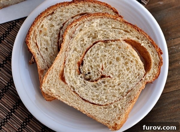 Golden Cinnamon Swirl Loaf 4 Two pieces of golden-brown cinnamon swirl toast, perfectly browned and topped with a sprinkle of cinnamon sugar, presented on a white plate for a delightful breakfast.
