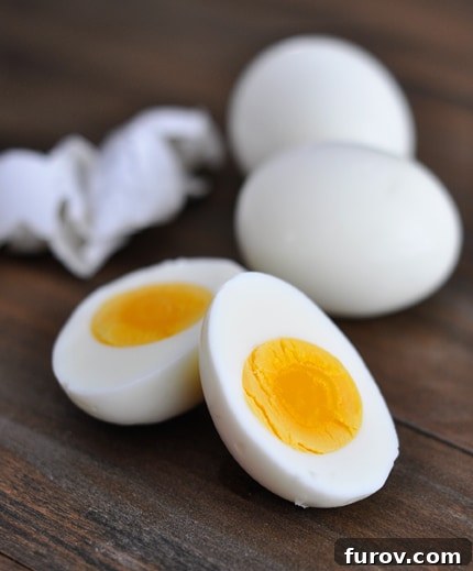A perfectly cooked hard-boiled egg cut in half, showing a firm, golden yolk.