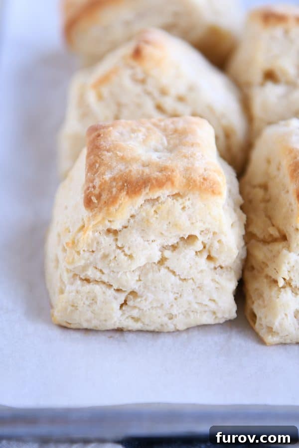 A platter brimming with several super flaky, golden brown buttermilk biscuits, showcasing their beautifully layered texture.