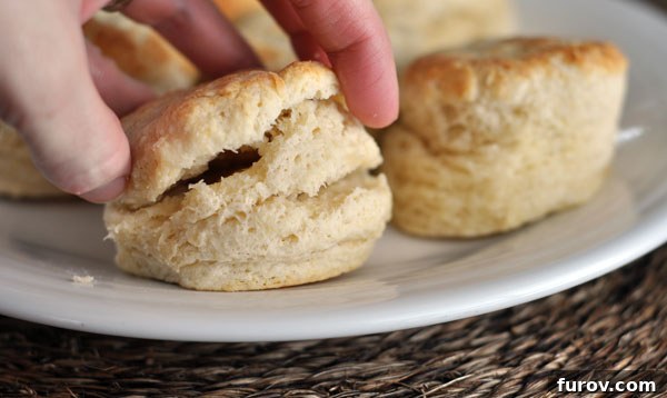 A white plate elegantly holding a stack of freshly baked, golden buttermilk biscuits.
