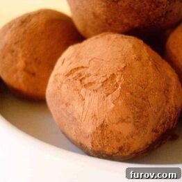A close-up of a perfectly rolled chocolate cream cheese truffle.