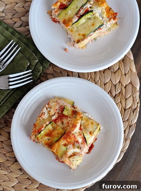 Top-down view of two servings of homemade zucchini lasagna on white plates, showcasing the layers.