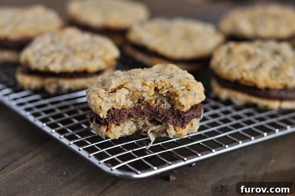 Fudge filled cookies on a cooling rack with one cookie having a bite taken out of it, revealing the fudge filling.