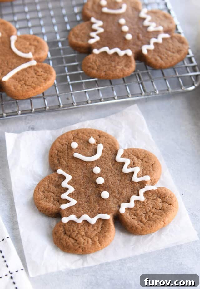 Soft gingerbread person cookie on piece of white parchment paper decorated with icing.