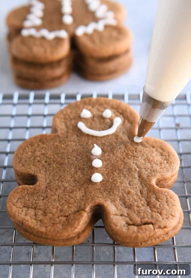 Piping decorations on gingerbread cookie with white icing.
