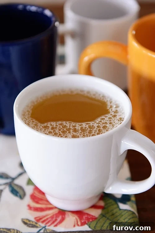 A white mug of tea with other empty mugs behind it. A perfect warm drink for a cold day.