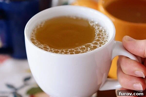 Hand holding a white mug of tea. A cozy and inviting drink.