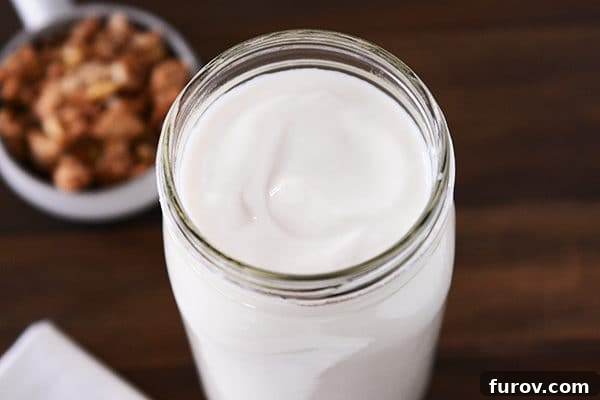 A top-down view of a clear mason jar filled with freshly made homemade yogurt, ready for enjoyment.