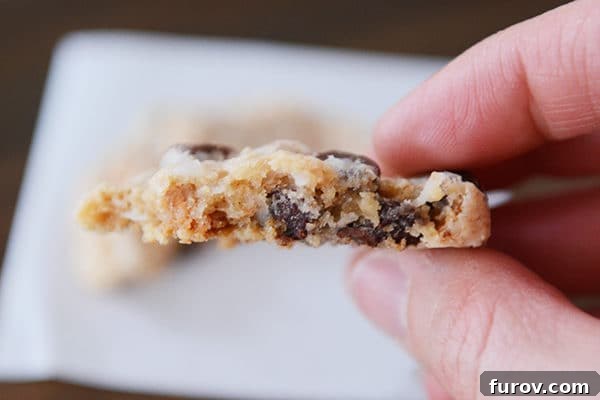 A close-up view of the interior of a half-eaten 7-Layer cookie, showcasing its moist, chewy texture and melty chocolate and butterscotch chips.
