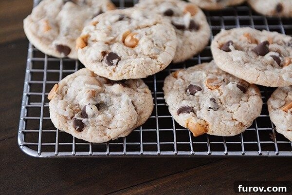 Freshly baked 7-Layer cookies cooling on a wire rack, showcasing their golden edges and abundant mix-ins.