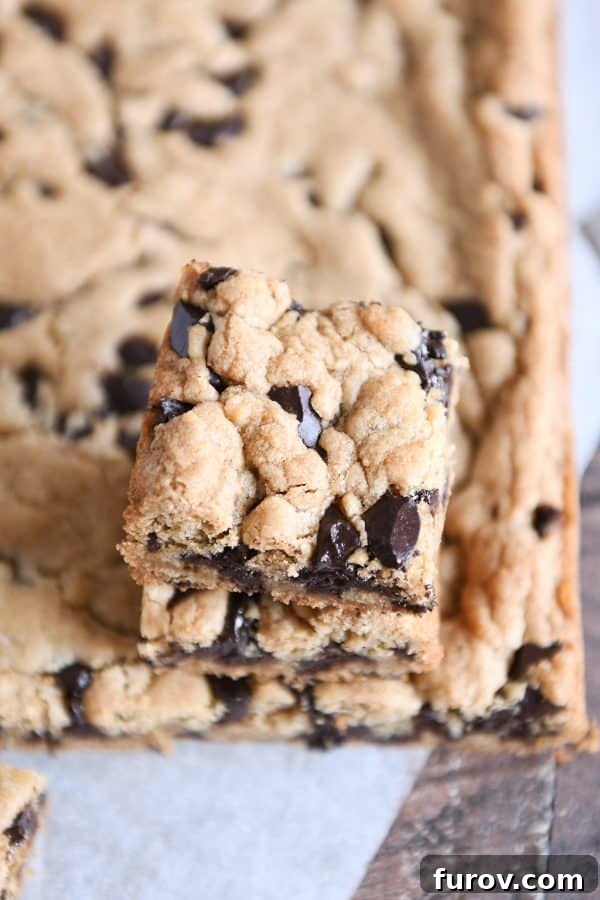 Two chocolate chip cookie bars stacked, showcasing their thick, chewy texture and rich chocolate chips.