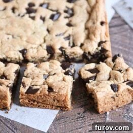 A golden slab of baked chocolate chip cookie bars, freshly cut into perfect squares.