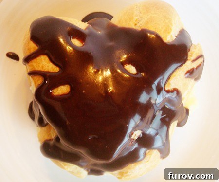 Top view of a heart shaped cream puff covered in chocolate sauce, ready to be enjoyed.