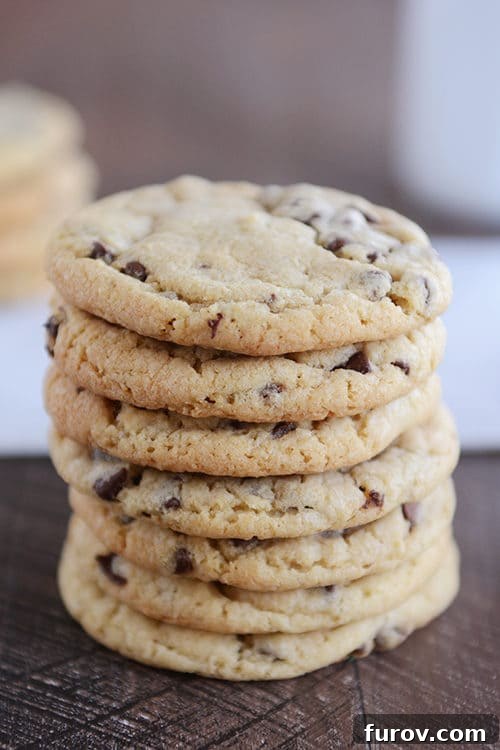 A stack of chocolate chip cookies on a brown table.