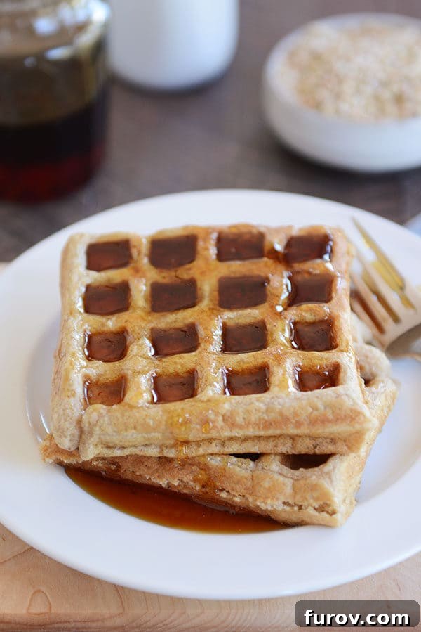 Two thick waffles covered in syrup on a white plate, ready to be enjoyed.