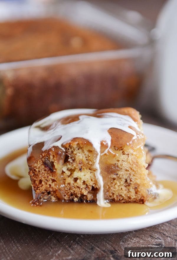 A piece of cake with light brown sauce and cream around and top of the cake.