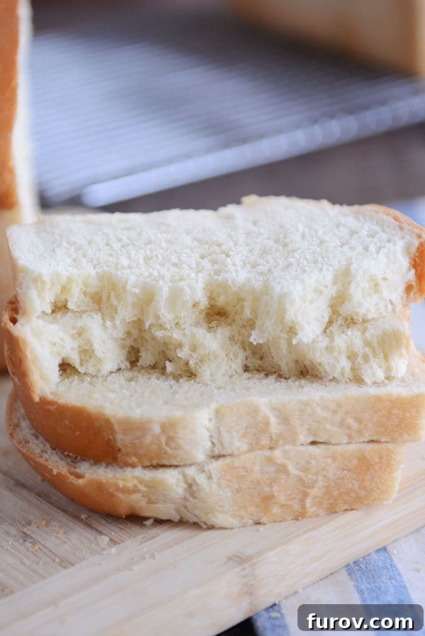 Four perfectly stacked slices of fluffy white bread, with the top two slices gently torn to reveal the soft interior.