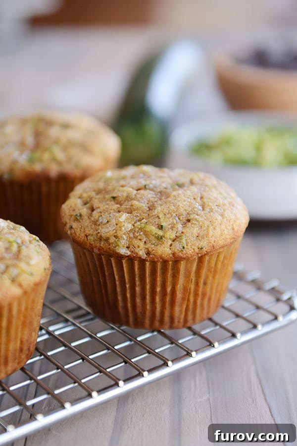 Ultimate Wholesome Zucchini Muffins 3 Warm, freshly baked zucchini muffins cooling on a wire rack, steam gently rising, showcasing their perfect dome tops and inviting appearance.