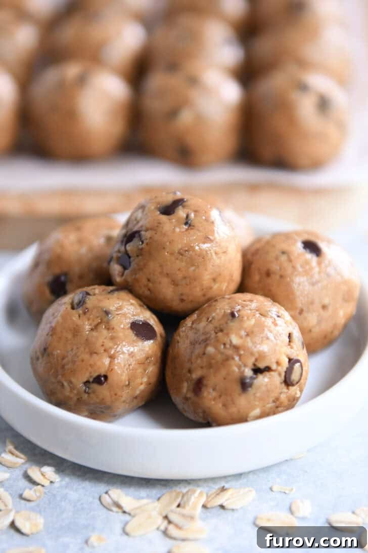 Close-up of three peanut butter chocolate chip protein bites stacked in a small white dish, with more bites in the background.