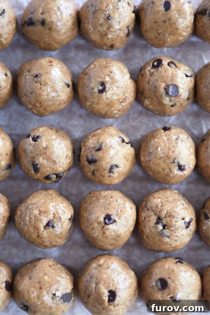 Top-down view of freshly rolled chocolate chip peanut butter protein bites arranged neatly on a sheet of wax paper.