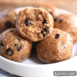 Soft peanut butter chocolate chip balls in a small white dish. The top ball has a bite taken out.