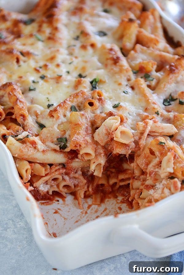 Dondurucu Dostu Fırında Peynirli Ziti 2 A casserole dish of cheesy baked ziti with a scoop taken out of the corner.