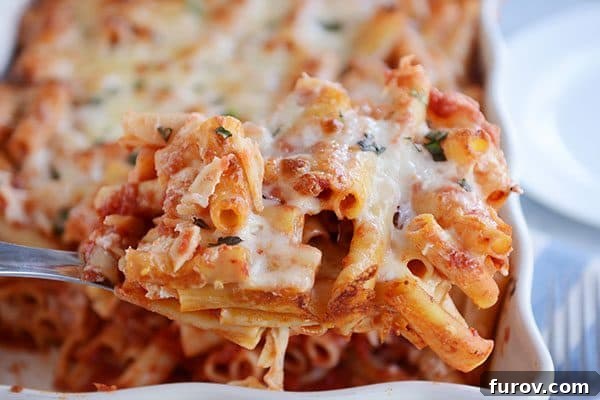 Dondurucu Dostu Fırında Peynirli Ziti 5 A large metal spoon taking a scoop of cheesy baked ziti out of a casserole dish.