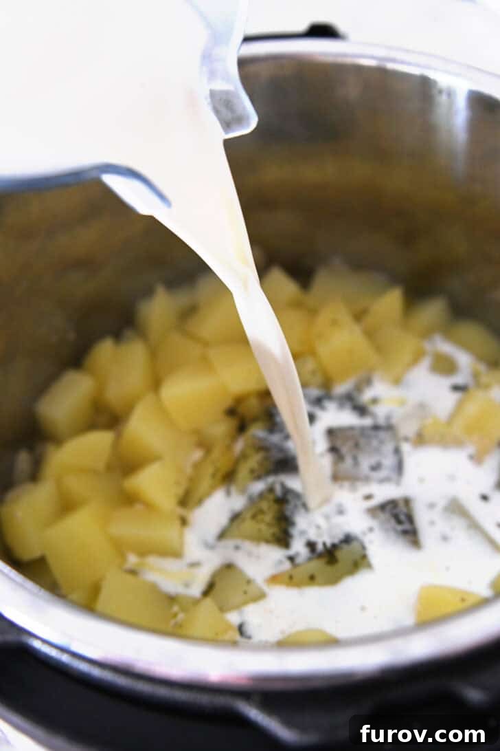 Pouring a creamy milk and cream cheese mixture into cooked potatoes inside an Instant Pot, thickening the soup.