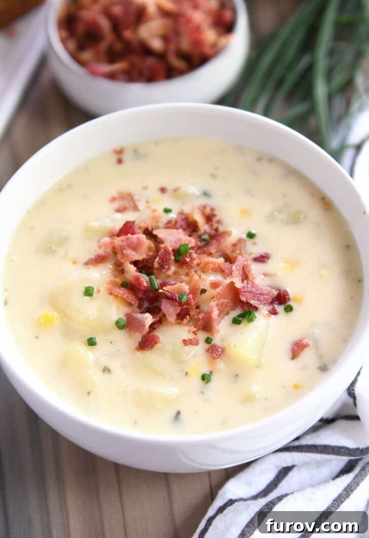 A white bowl brimming with creamy Instant Pot Cheesy Potato Soup, garnished with crispy bacon and fresh chives.